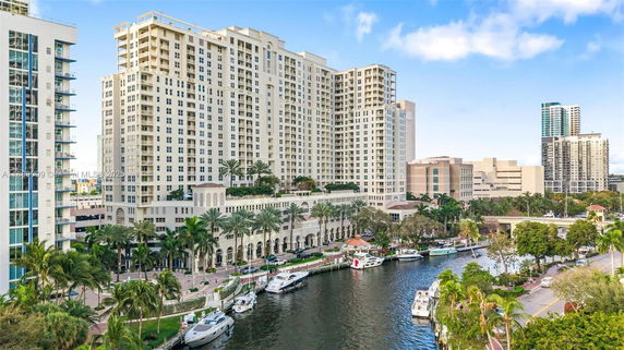 Front view of a large multi-story residential building with balconies overlooking a waterfront area.