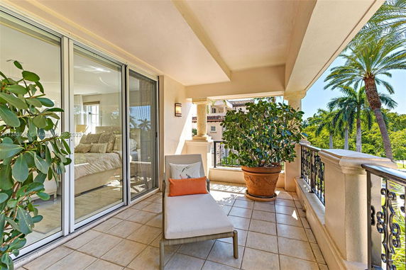 Balcony area with a lounge chair, potted plants, and sliding glass doors leading to a bedroom.