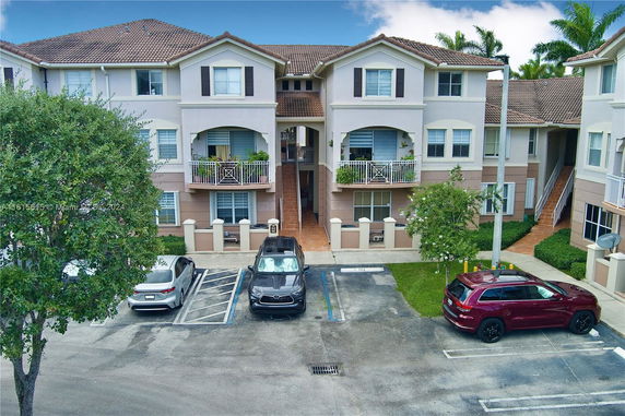 Front view of a multi-story residential building with balconies and a tile roof.