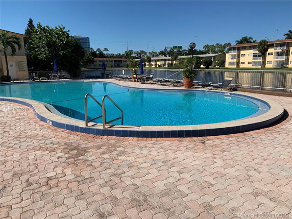 Outdoor swimming pool with surrounding paved area and loungers.