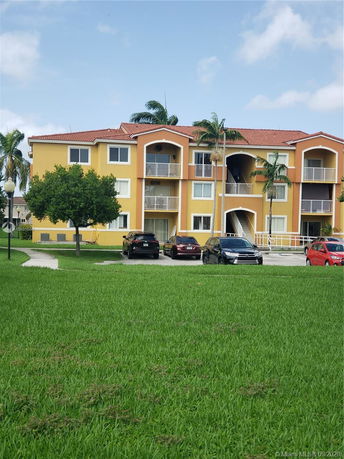 Front view of a three-story apartment building with a red-tiled roof and balconies.