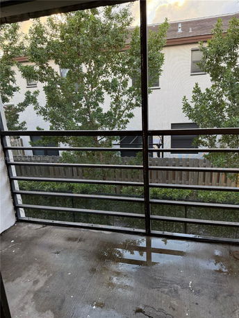 View from a balcony overlooking trees and a neighboring building.