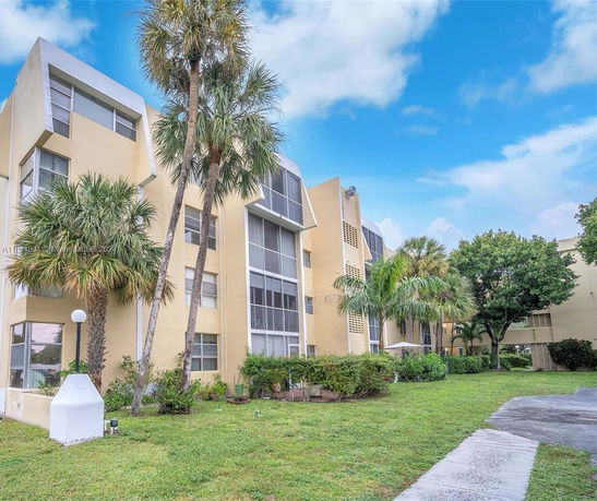 Front view of a multi-story residential building with palm trees.
