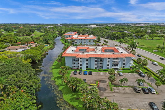 Aerial view of apartment buildings with a canal and surrounding greenery.