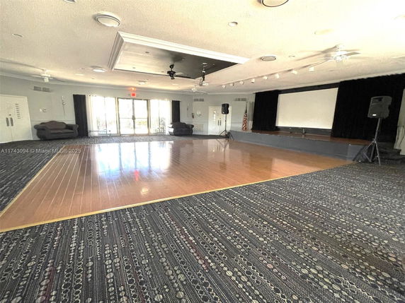 Large indoor room with a stage and wooden floor area for events and recreation.