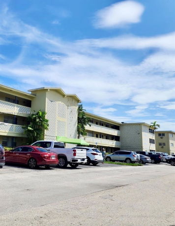 Front view of a multi-story residential building with parking area.
