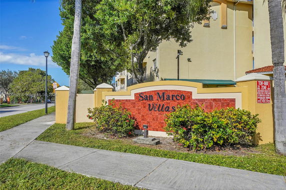 Front view of San Marco Villas sign with surrounding building visible.