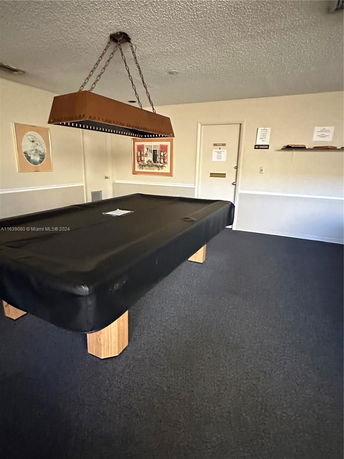 Room with a billiards table and overhead light fixture.
