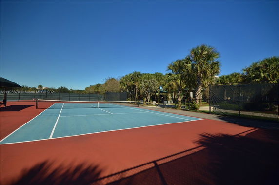 Outdoor tennis court surrounded by trees and greenery.