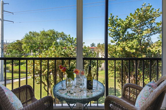 Balcony view overlooking trees and power lines with a round table and chairs.