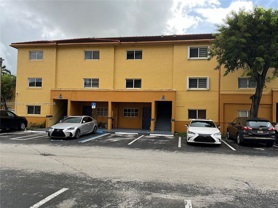 Front view of a three-story building with parking area.