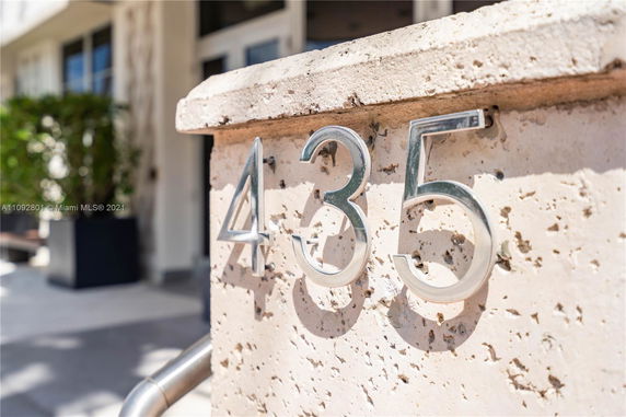 Close-up view of a building's address on a stone pillar with metal numbers 435.