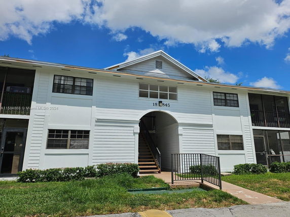 Front view of a two-story residential building with a central staircase and multiple windows.