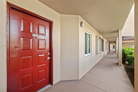 Exterior view of a building corridor with a red door and windows.