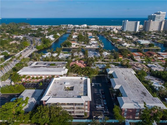Aerial view of a coastal urban area with residential buildings, canals, and a distant view of the ocean.