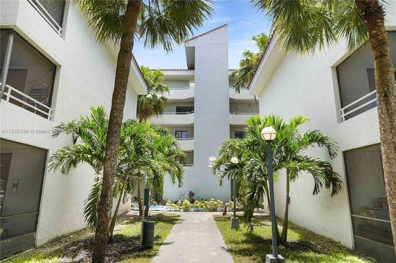 Front view of a multi-story building with balconies and palm trees.
