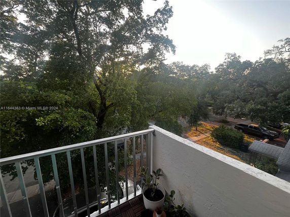 View from a balcony overlooking a street and trees.