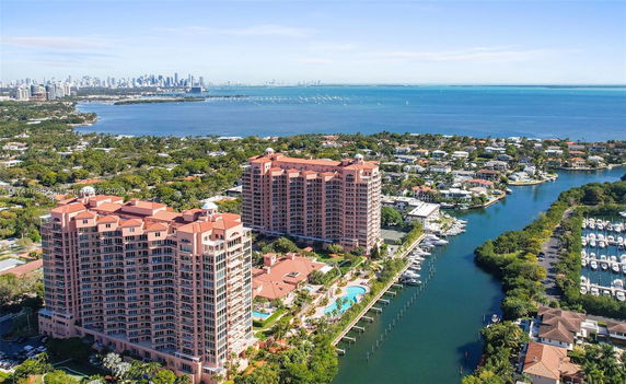 Panoramic view of coastline with tall residential buildings, marina, and city skyline in the distance.