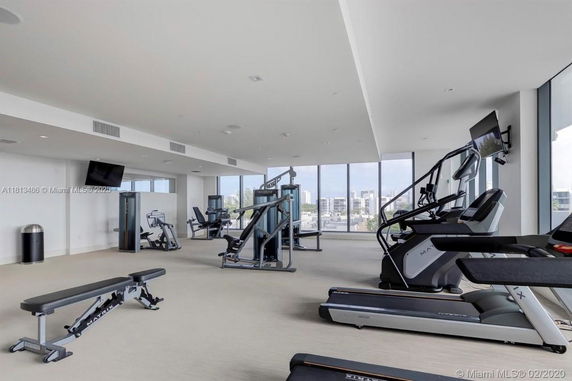 View of an indoor gym with exercise machines and large windows.