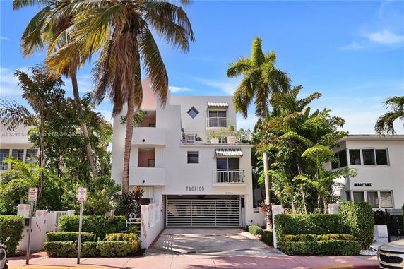 Front view of a multi-story building with balconies and palm trees.