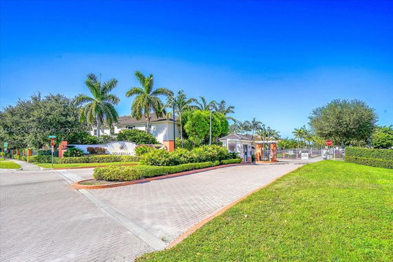 Entrance view of a gated residential community with palm trees and landscaped gardens.