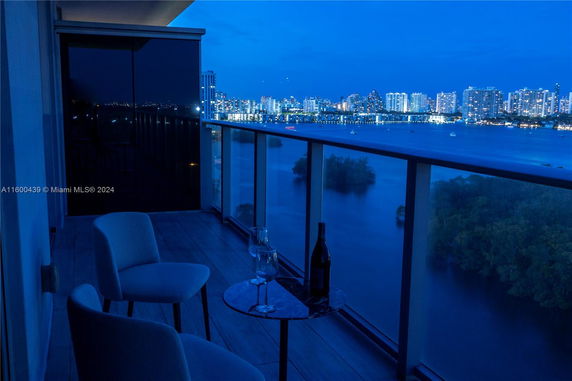Balcony view overlooking a body of water with city skyline in the background.