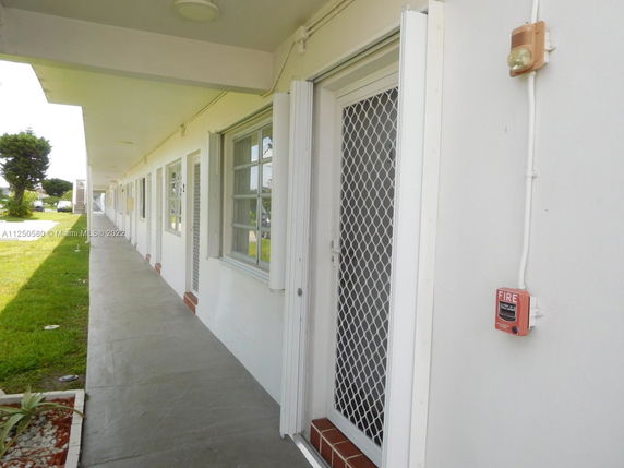 View of a linear building facade with multiple doors and windows along a walkway.