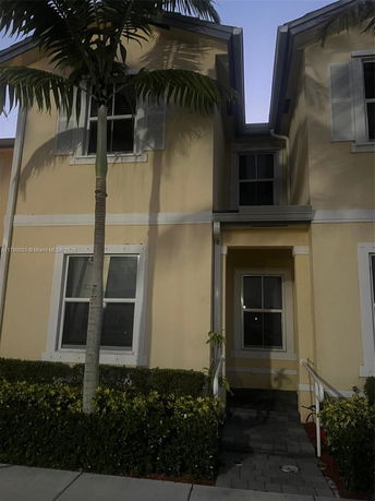 Front view of a two-story house with a small porch and white framed windows.