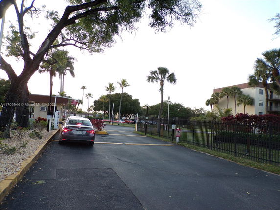 Driveway leading to a gated entry with a parking area beside a residential building.