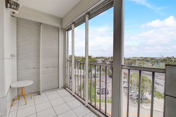 Enclosed balcony with a view of parking lot and sports fields.