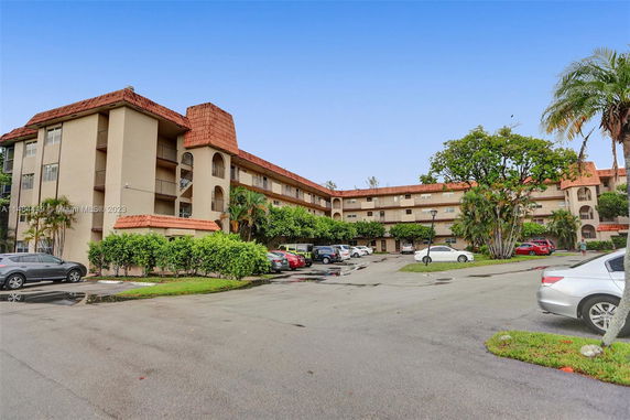 Front view of a multi-story apartment building with parking area.