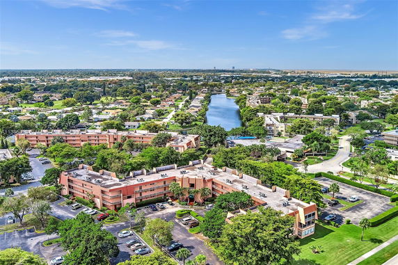 Aerial view of residential buildings surrounded by greenery and a waterway.