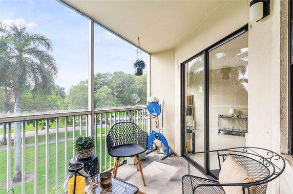 Balcony view from within a building showing surrounding greenery and trees.