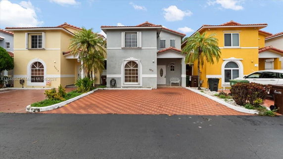 Front view of a two-story house with a red-tiled roof and paved driveway.