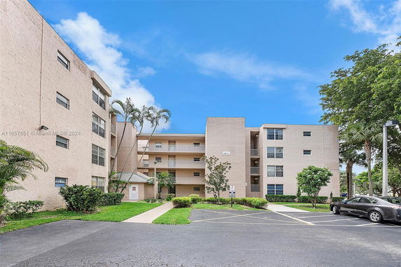 Front view of a multi-story residential building with balconies and parking area.