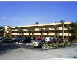 Front view of a multi-story building with parked cars in front.