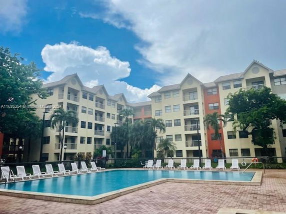 Apartment complex with a swimming pool in front.