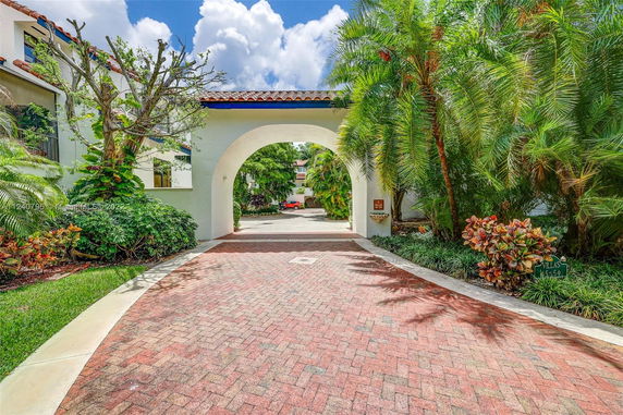 Front view of a house with an arched entrance and brick driveway.