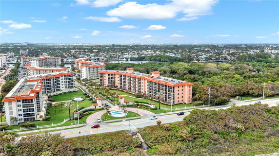 Aerial view of residential buildings with orange roofs surrounded by greenery.