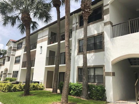Front view of a multi-story residential building with balconies and palm trees.