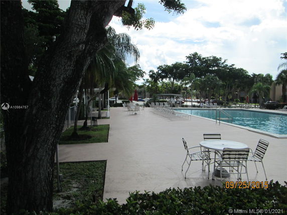Outdoor swimming pool area with surrounding seating and trees.