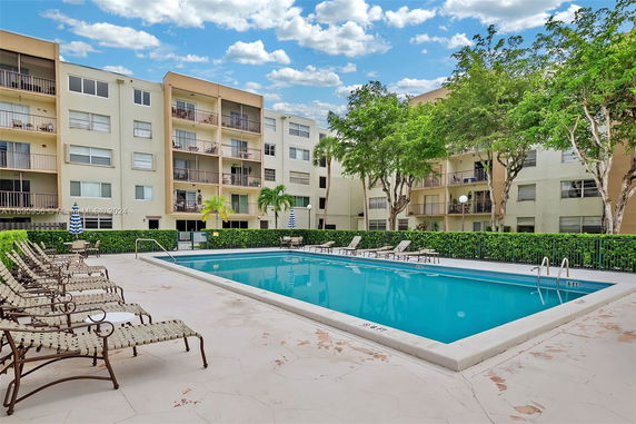 Outdoor swimming pool area surrounded by multi-story residential buildings.