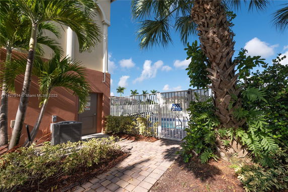 Outdoor entrance to a gated swimming pool area with a 'pool closed' sign.