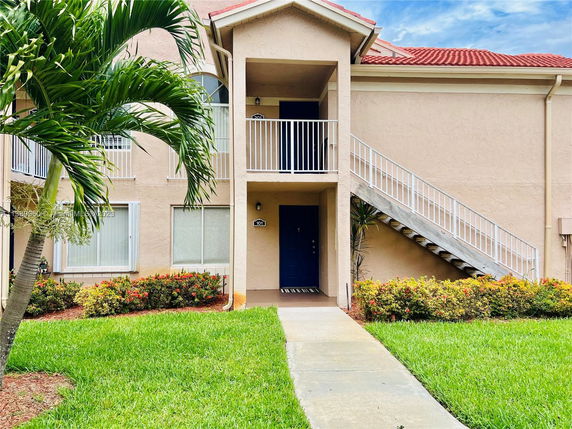 Front view of a two-story residential building with an exterior staircase and garden.