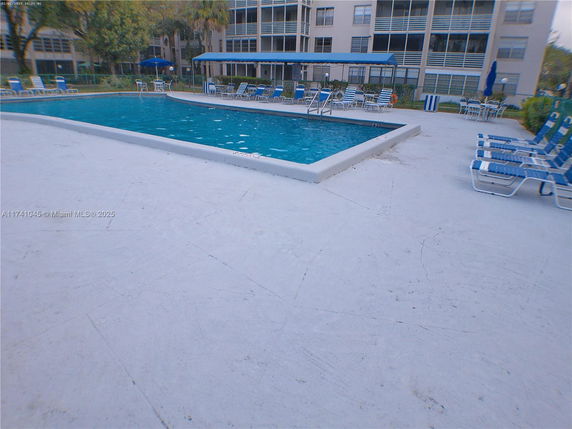 Outdoor swimming pool area with lounge chairs and surrounding building.