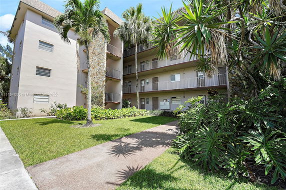 Front view of a multi-story residential building with balconies and a landscaped pathway.