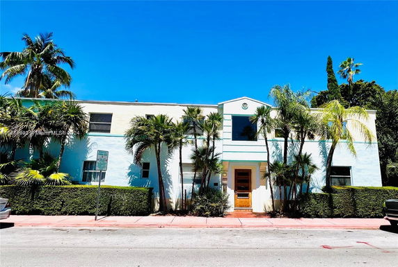 Front view of a two-story house with palm trees.