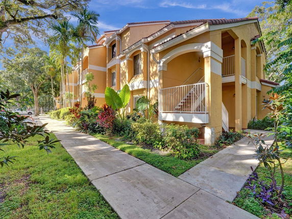 Front view of a multi-story building with a staircase and tropical landscaping.