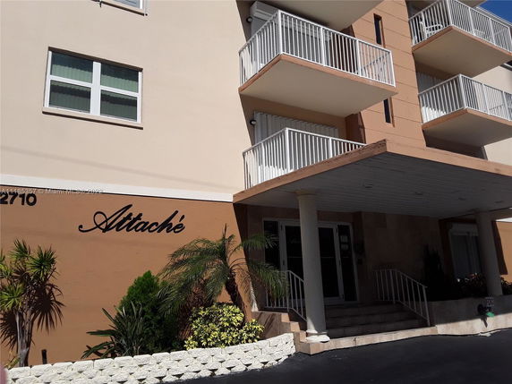 Front view of a multi-story building with balconies and entrance.