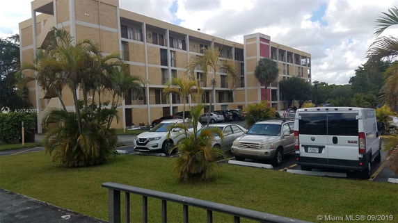 Front view of a multi-story residential building with a parking area.